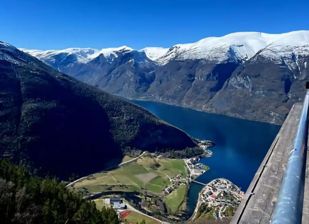 The Aurlandsfjord and the village of Flåm seen from high above, with snow-capped peaks behind.