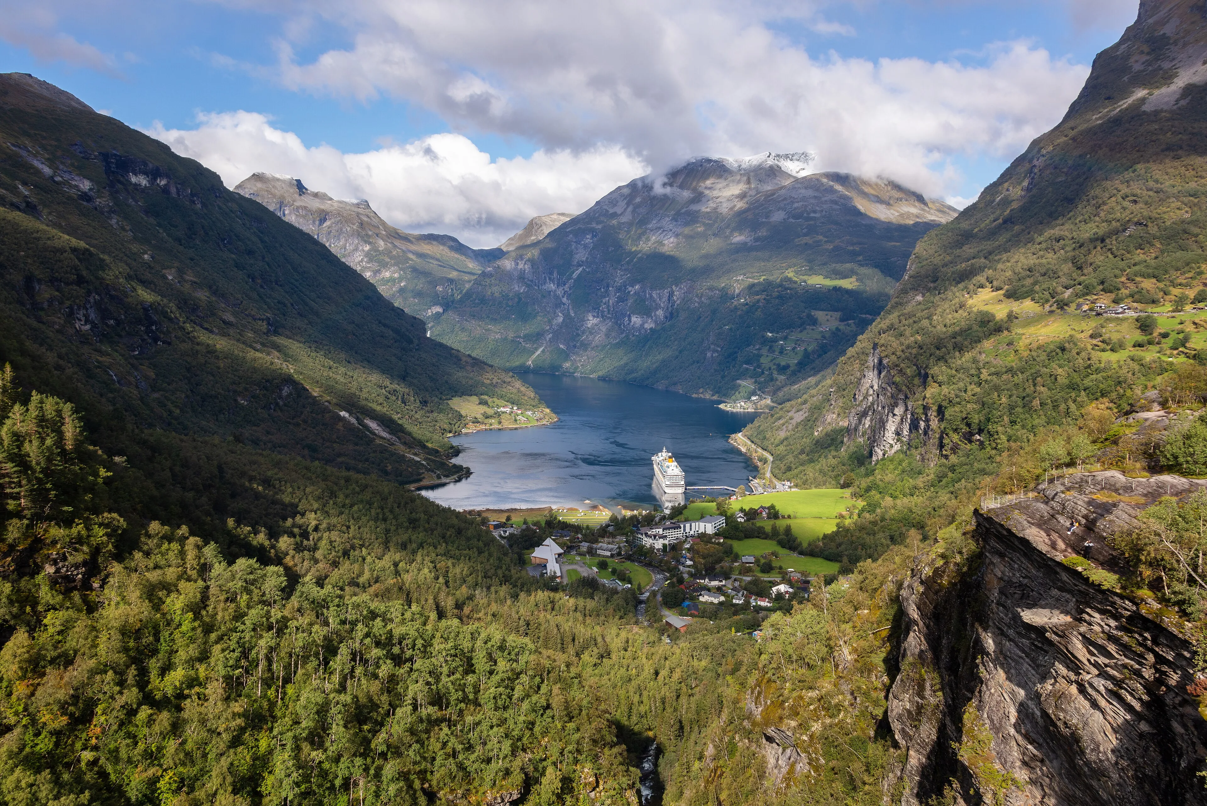 The Geirangerfjord and the village of Geiranger seen from the Flydalsjuvet viewpoint, with a cruise ship far below.
