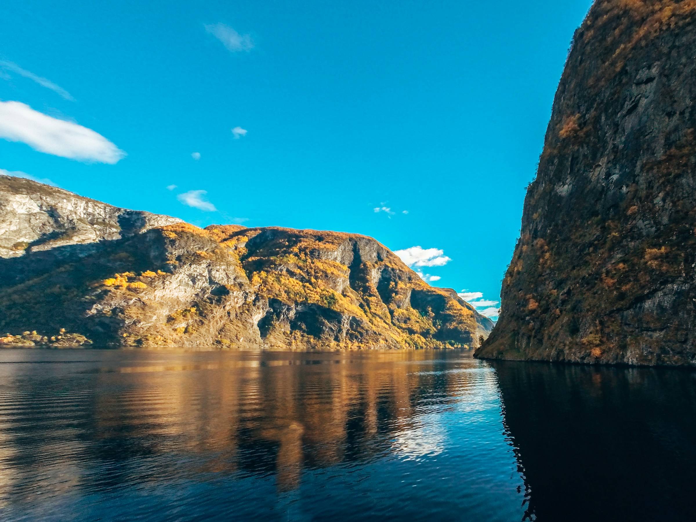 A RIB boat at the foot of a waterfall on the Nærøyfjord near Flåm.