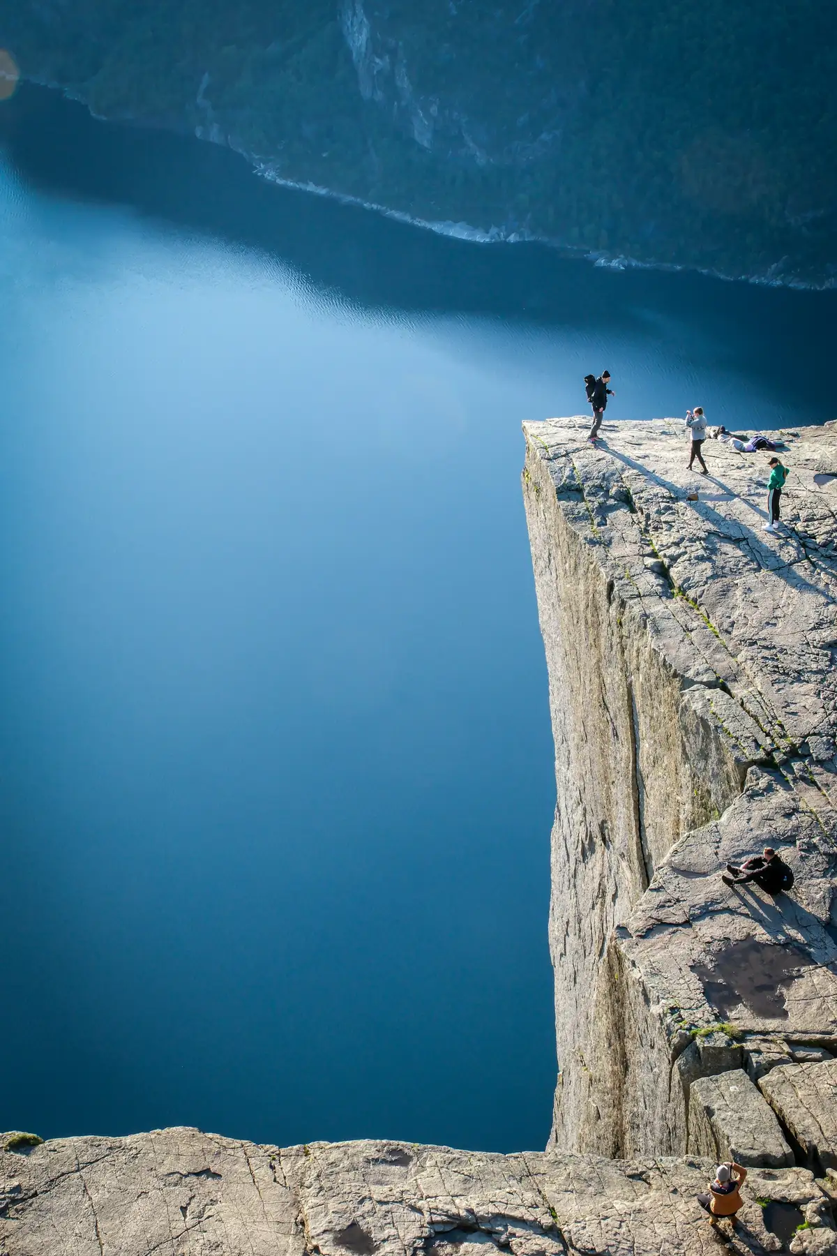 Hikers standing on the Preikestolen cliff plateau above Lysefjord.