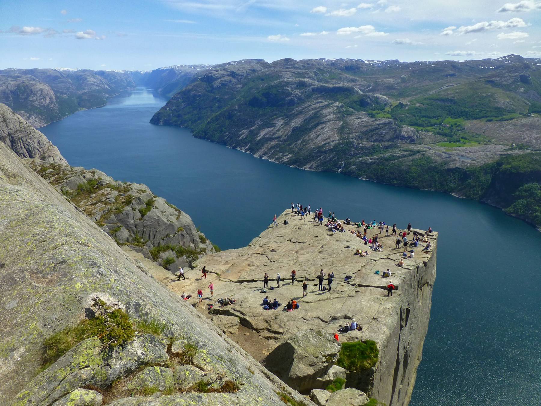 People standing on the flat Pulpit Rock plateau above Lysefjord.